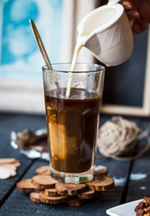 add cream to black coffee cup, hand