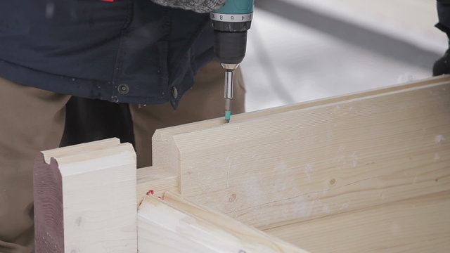 Builder spins screw screwdriver in the design of wooden Finnish
