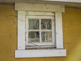 Abandoned yellow house with broken window