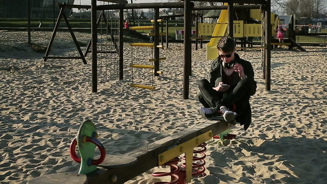 Happy student smiling to the camera on seesaw and texting 