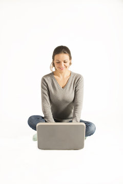 Woman sitting cross legged on floor typing on laptop