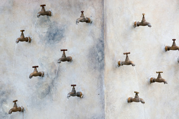 Many water taps mounted on the wall - obrazy, fototapety, plakaty