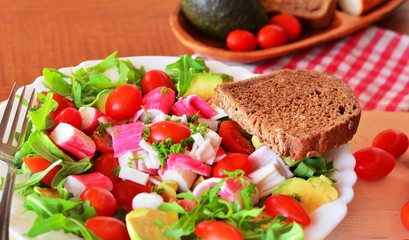 Mixed vegetable salad with crab sticks and avocado