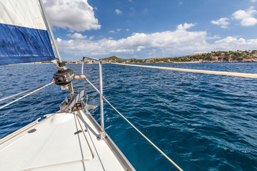 Obraz premium Nose boat with a sail on the background of the shore