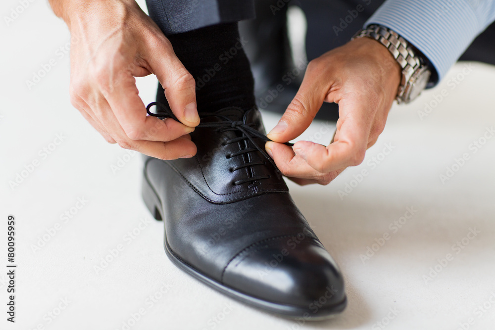 Wall mural close up of man leg and hands tying shoe laces