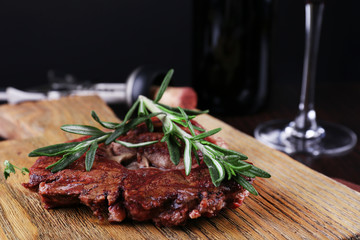 Grilled steak with bottle of wine on dark background