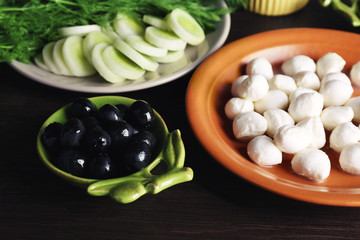 Fototapeta na wymiar Mozzarella cheese with olives and greens on wooden background