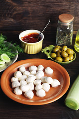 Mozzarella cheese with olives and greens on wooden background