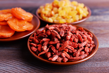 Dried fruits in small plates on rustic wooden table background