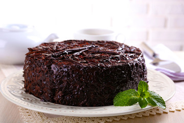 Tasty chocolate cake on table on brick wall background