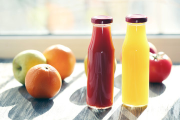 Bottles of juice with fruits and vegetables on windowsill