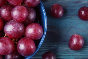 Close up of grapes with water drops in blue plate on wooden tabl