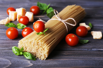Raw pasta with tomatoes and cheese on wooden background