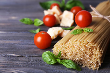 Raw pasta with tomatoes and cheese on wooden background