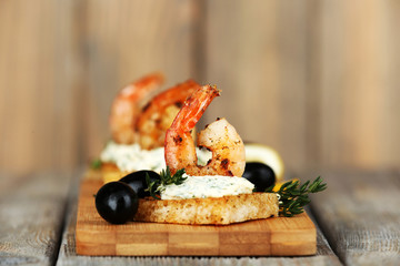 Appetizer canape with shrimp and olives on wooden background © Africa Studio