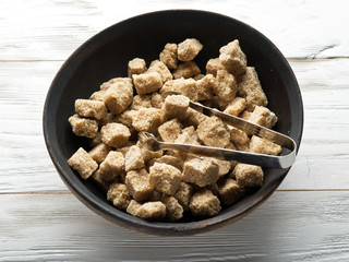 Cubes of cane sugar on wooden table.