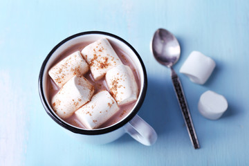 Mug of cocoa with marshmallows on wooden table background