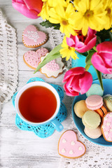 Composition of spring flowers, tea and cookies on table