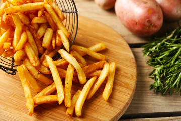 Tasty french fries in metal basket on wooden table background