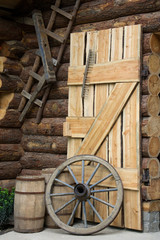 Obraz premium Log cabin with door, barrels and wheel