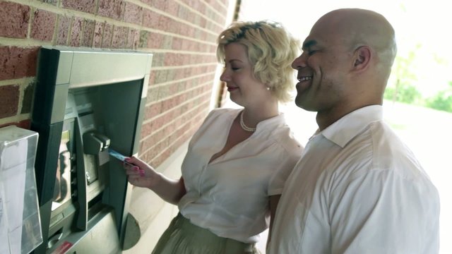 Man and woman use an ATM and look at each other accusingly when they discover the money has gone.  Camera mounted on slider.