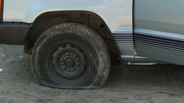 Driver discovers she has a flat tire, gets out of her vehicle and calls for roadside assistance.