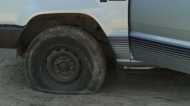 Driver discovers he has a flat tire, gets out of his truck and calls for roadside assistance.