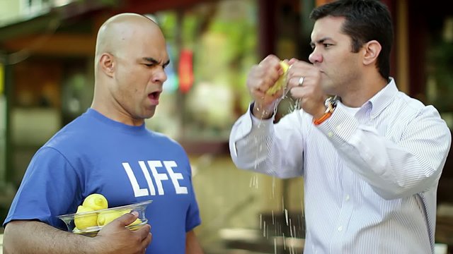 Man rips up a lemon after taking it from a guy in a blue T-shirt that says "LIFE".