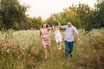 Girl jumpling over hand in hand with parents