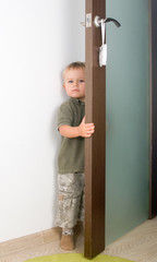 Serious 2-year boy handling a door - 80117166