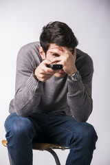 Young man with remote control, covering his eyes scared