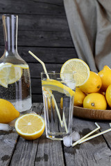Lemonade in a transparent glass and lemons on a  wooden table