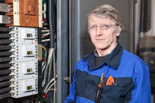 Electrician repairman in work wear stands near high voltage box