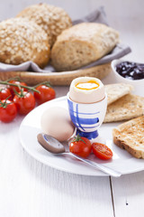 Soft-boiled egg in the morning with toast. In the background of