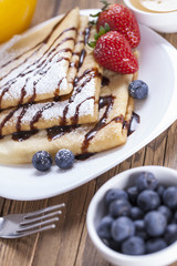 Delicious sweet French pancakes on a plate with fresh fruits
