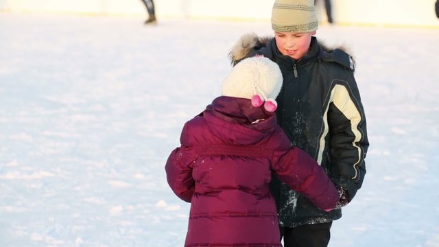 Brother and sister learn to skate together hand in hand