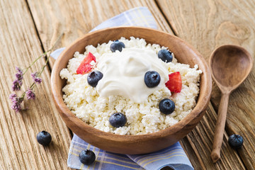Cottage cheese with sour cream and ripe blueberries in a wooden