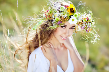 Beautiful woman in a summer field with flower wreath