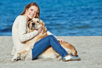 girl are playing with a dog on the beach