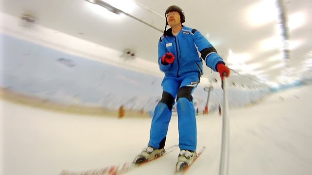 Man goes on skis on mountain slope in ski complex 