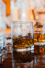 whiskey glass with ice and warm light on black table