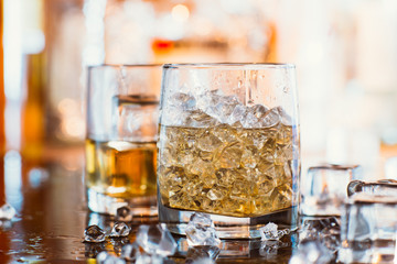 whiskey glass with ice and warm light on black table