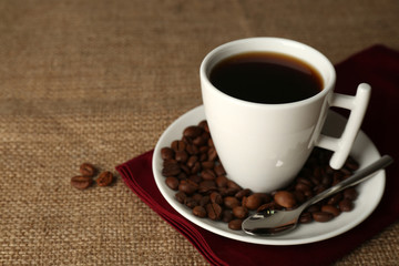 Cup of coffee with beans on rustic wooden background