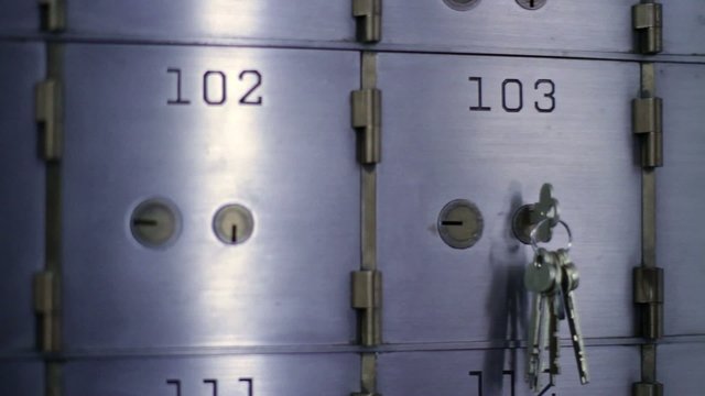 Woman Unlocks A Safe Deposit Box And Removes Contents, Then Replaces Them And Closes Door Again.  Detail Shot Inside Bank Vault, Camera Mounted On Slider.