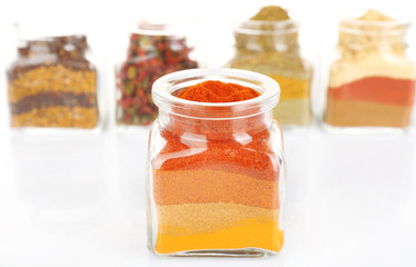 Different kinds of spices in glass bottles isolated on white