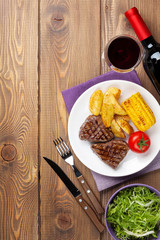 Steak with grilled potato, corn, salad and red wine