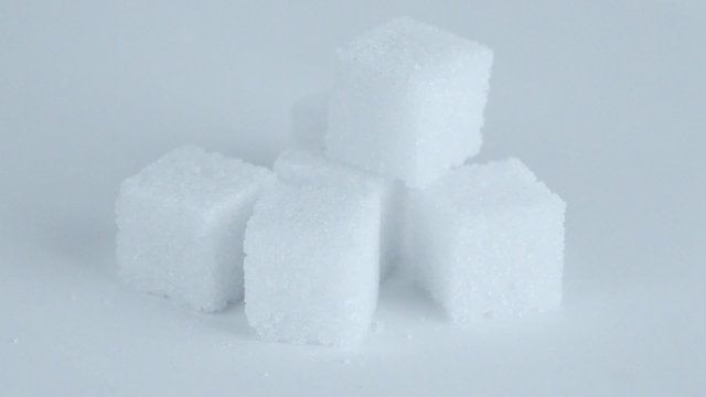 Five lump sugar cubes circling closeup at white background