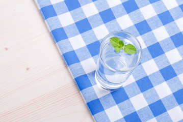 glass of clean water with mint on a table covered with a checker