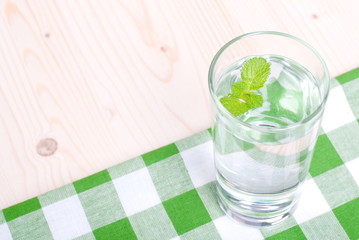 glass of clean water with mint on a table covered with a checker