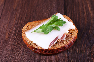 Sandwich with lard and parsley on wooden background
